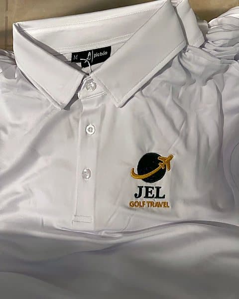 A white Pichón polo with the JEL Golf Travel logo embroidered on the chest