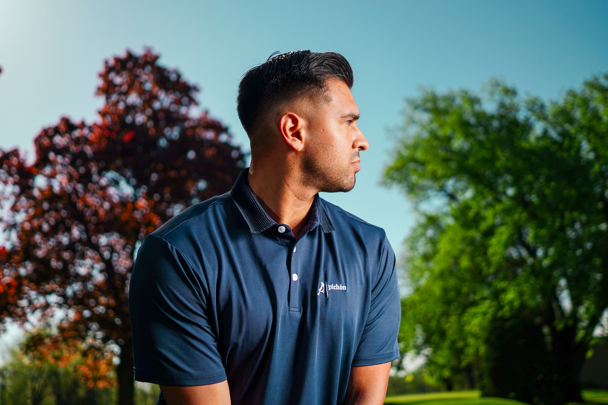 A golfer in a navy Pichón polo on a parkland course